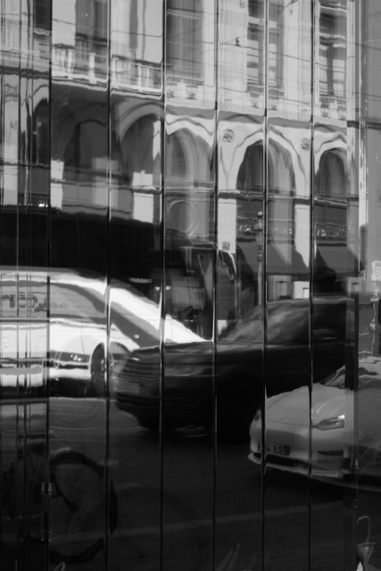 Im Spiegel eines Schaufensteres, spiegelt sich die Straße und der Verkehr, schwarz-weiß